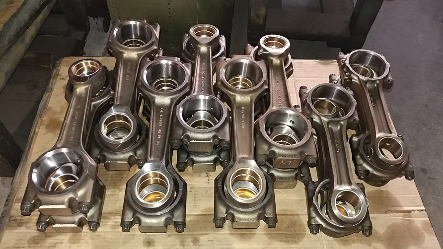 Technician inspecting connecting rod bushing wear and small-end fit at Motor Service Group in Miami