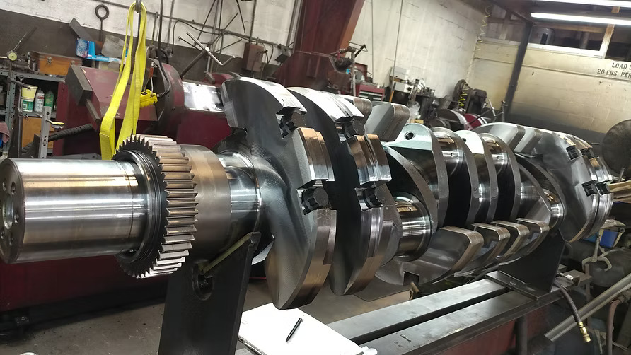 Technician inspecting a diesel engine crankshaft at a machine shop in Miami
