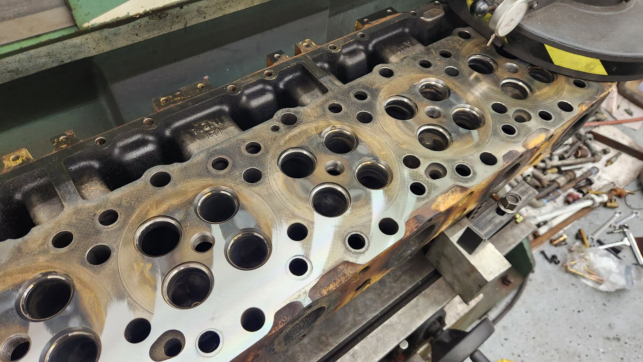 Diesel cylinder head undergoing valve grinding and crack detection at Motor Service Group machine shop in Miami, FL