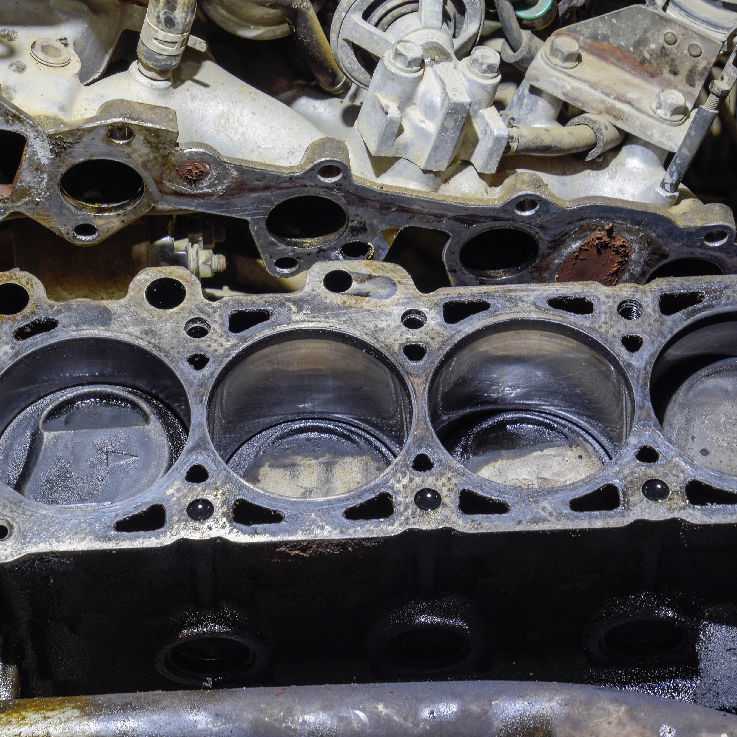 Disassembled four-cylinder engine block showing the head gasket surface and open cylinder bores.